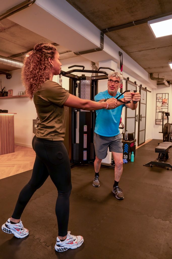 Trainer begeleidt een klant bij een oefening met weerstandsband